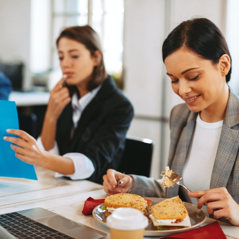 Young business woman eating breakfast in the office